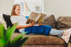 Girl sitting on a lounge reading a book with the Harkla Weighted Blanket Lap